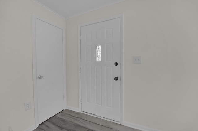 foyer entrance with crown molding, baseboards, and wood finished floors