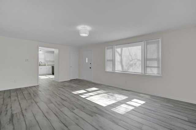 spare room with a sink, baseboards, and wood finished floors