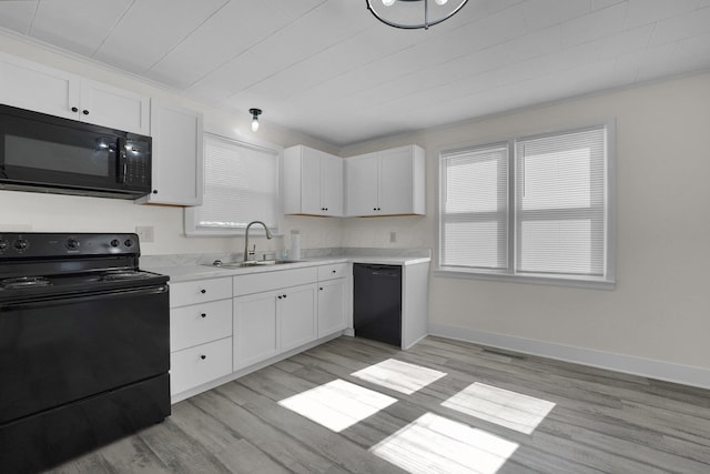 kitchen featuring white cabinets, black appliances, and a sink