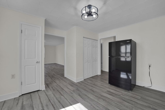 interior space featuring crown molding, light wood-style flooring, and baseboards