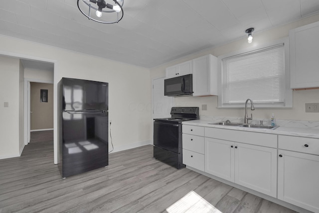 kitchen featuring white cabinets, black appliances, light wood-type flooring, and a sink