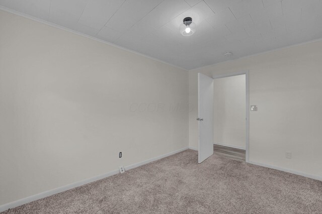 empty room featuring baseboards, carpet floors, and ornamental molding