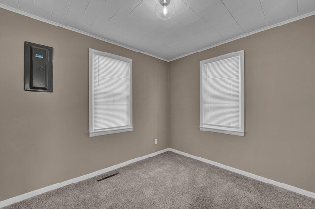 carpeted empty room featuring crown molding, electric panel, visible vents, and baseboards