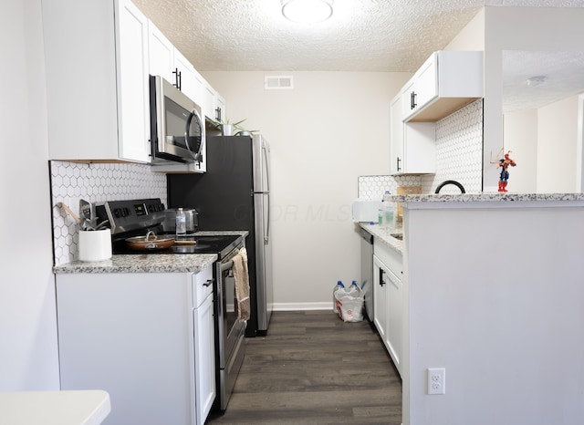 kitchen featuring visible vents, appliances with stainless steel finishes, white cabinetry, and dark wood-style flooring