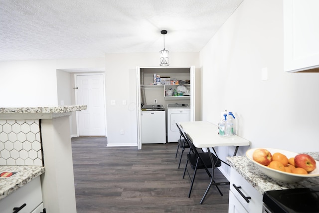 kitchen with dark wood-type flooring, a textured ceiling, white cabinetry, separate washer and dryer, and baseboards