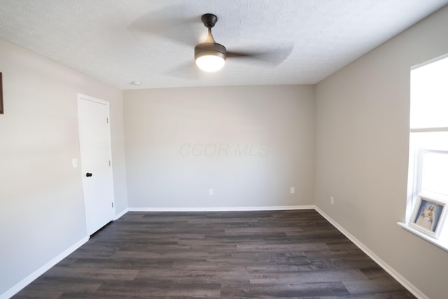 empty room with ceiling fan, dark wood-style floors, baseboards, and a textured ceiling