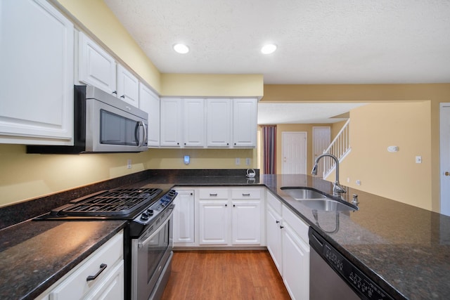 kitchen with a sink, stainless steel appliances, light wood-type flooring, and white cabinetry