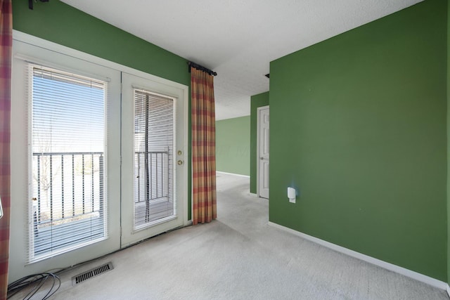 carpeted spare room featuring visible vents and baseboards