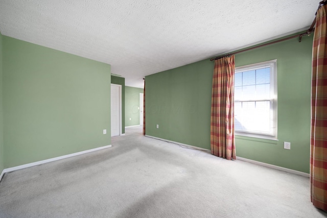 carpeted spare room featuring baseboards and a textured ceiling