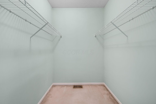 walk in closet featuring visible vents and light carpet