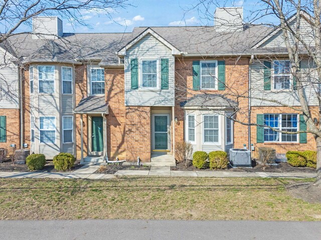 townhome / multi-family property featuring cooling unit, entry steps, a chimney, and a front yard