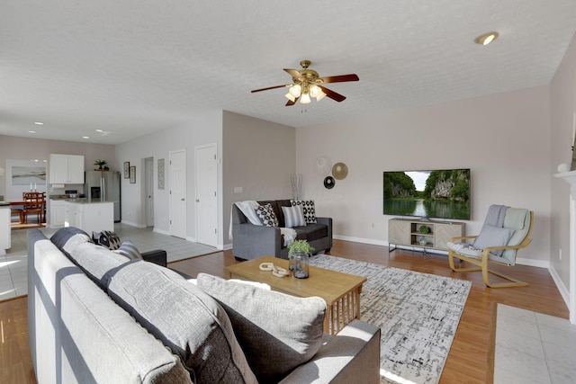 living room featuring light wood finished floors, baseboards, recessed lighting, a textured ceiling, and a ceiling fan