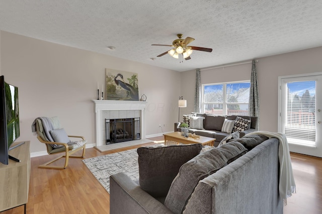 living area featuring a wealth of natural light, wood finished floors, a fireplace, and ceiling fan