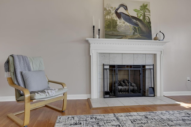 living area with baseboards, wood finished floors, and a fireplace