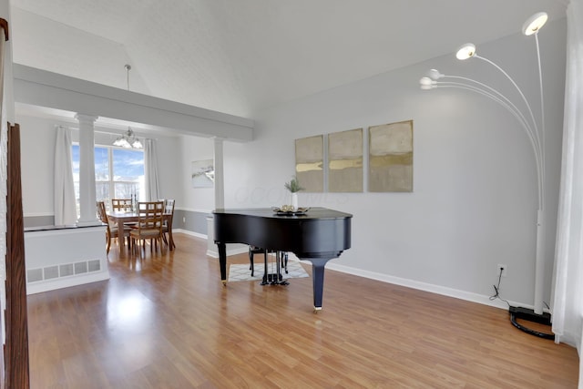 living area with light wood-style floors, baseboards, and ornate columns