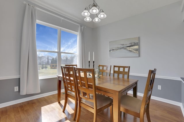 dining space with a notable chandelier, baseboards, and wood finished floors