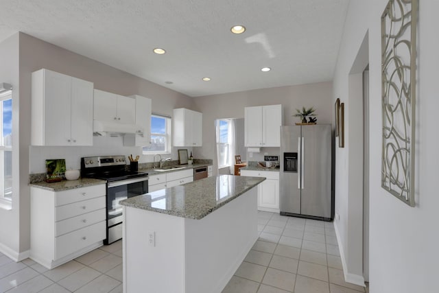 kitchen featuring under cabinet range hood, a sink, a center island, appliances with stainless steel finishes, and white cabinets