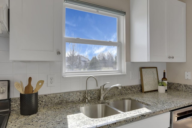 kitchen featuring dishwasher, white cabinets, backsplash, and a sink