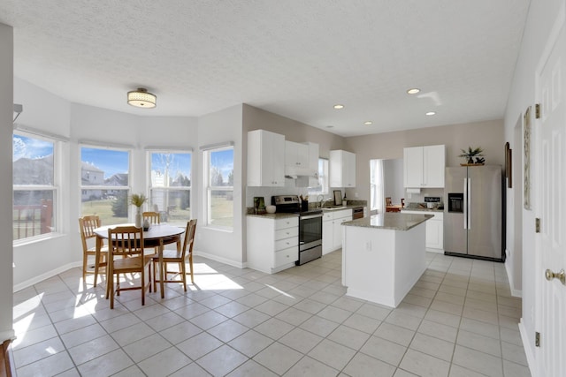 kitchen featuring a center island, light tile patterned floors, appliances with stainless steel finishes, a textured ceiling, and white cabinetry