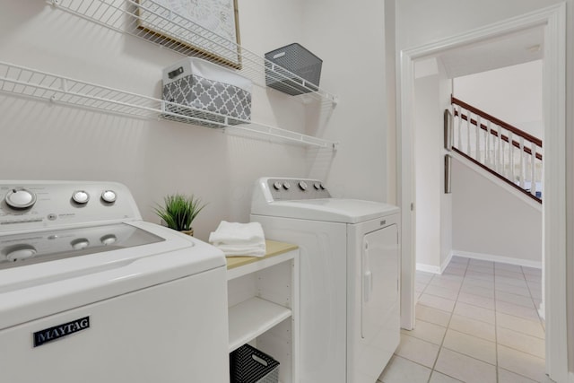 clothes washing area with light tile patterned flooring, laundry area, baseboards, and separate washer and dryer