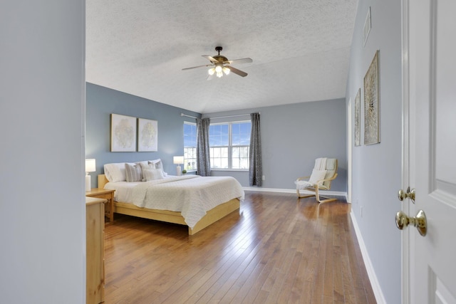 bedroom featuring visible vents, baseboards, a textured ceiling, and hardwood / wood-style flooring