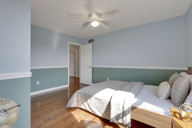 bedroom featuring visible vents, a ceiling fan, baseboards, and wood finished floors