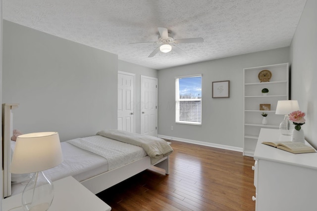 bedroom featuring a textured ceiling, a ceiling fan, baseboards, and hardwood / wood-style flooring