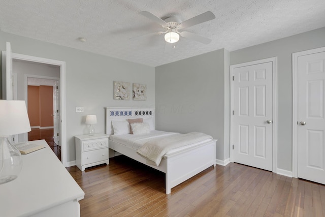 bedroom with baseboards, a textured ceiling, and wood finished floors