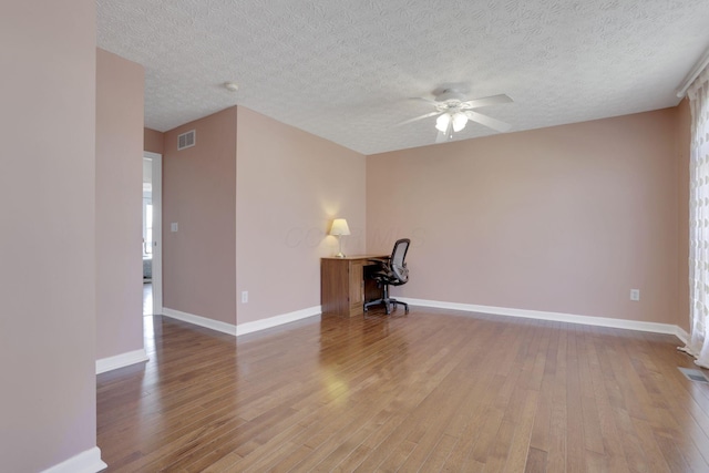 unfurnished room featuring baseboards, a textured ceiling, wood finished floors, and a ceiling fan