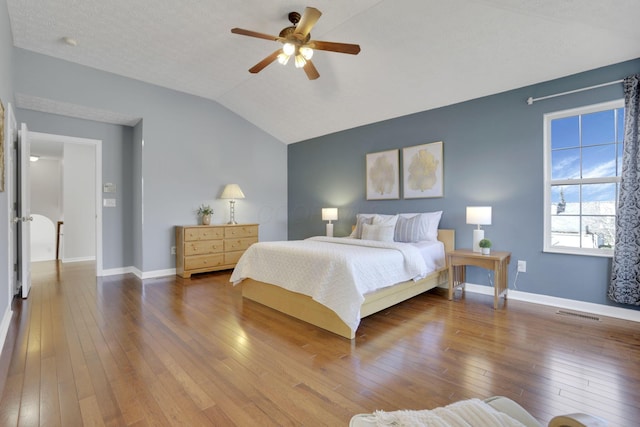 bedroom featuring lofted ceiling, baseboards, wood-type flooring, and ceiling fan