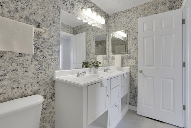 bathroom featuring wallpapered walls, toilet, tile patterned floors, a textured ceiling, and a sink