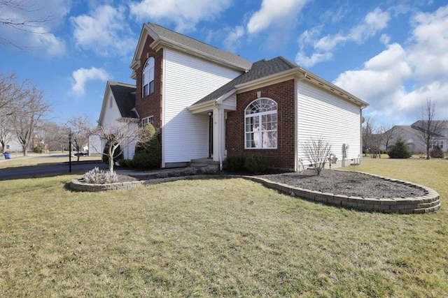 view of side of property with brick siding and a lawn