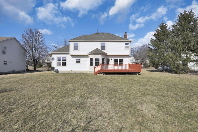 rear view of property featuring a deck, a yard, a shingled roof, and a chimney