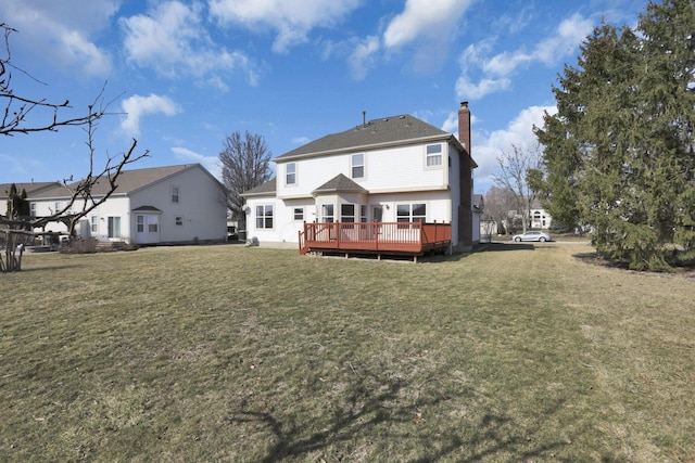 rear view of house with a lawn, a deck, and a chimney