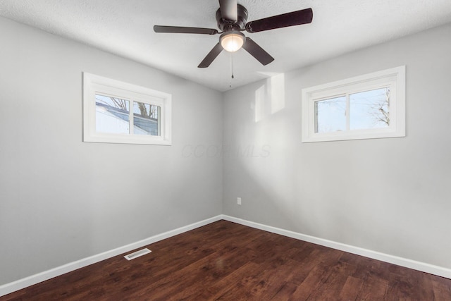 unfurnished room with a wealth of natural light, dark wood-type flooring, and baseboards