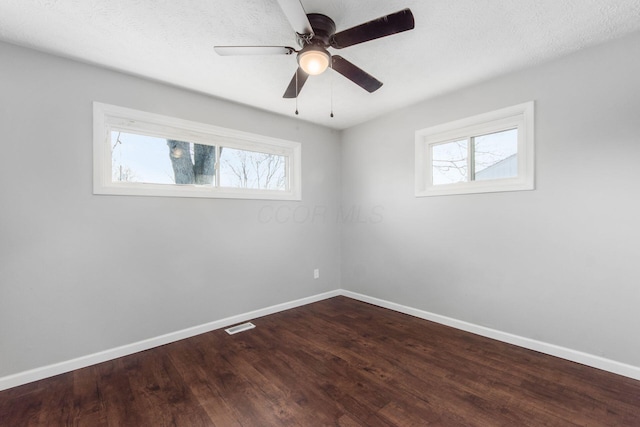 spare room with visible vents, baseboards, dark wood finished floors, and a ceiling fan