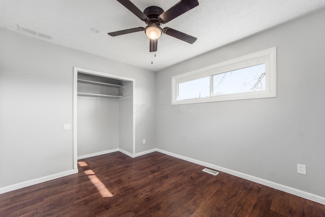 unfurnished bedroom featuring a closet, visible vents, baseboards, and wood finished floors