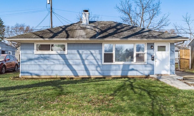 back of house with a lawn, a chimney, and fence