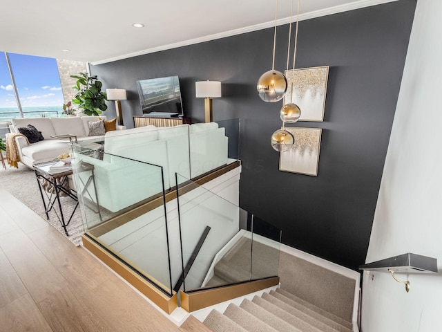 staircase featuring recessed lighting, crown molding, a wall of windows, and wood finished floors