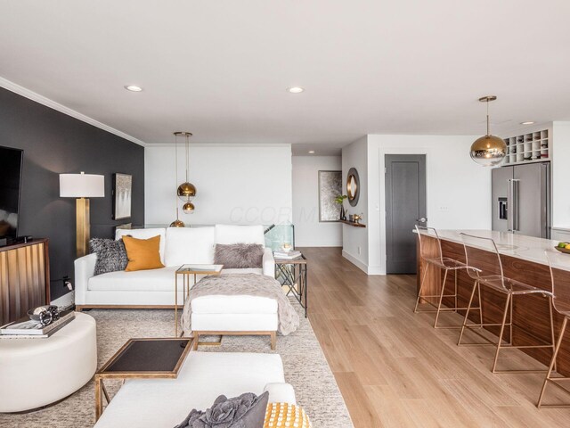 living area featuring recessed lighting, light wood-style floors, baseboards, and ornamental molding