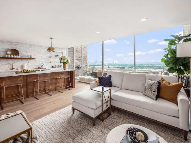 living room featuring indoor wet bar, recessed lighting, and light wood-style flooring