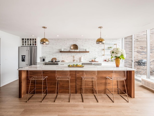 kitchen featuring a sink, light wood-type flooring, high quality fridge, and light countertops