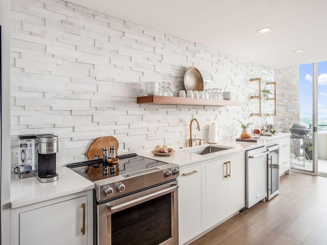 kitchen with a sink, white cabinetry, light wood-style floors, light countertops, and stainless steel electric range oven