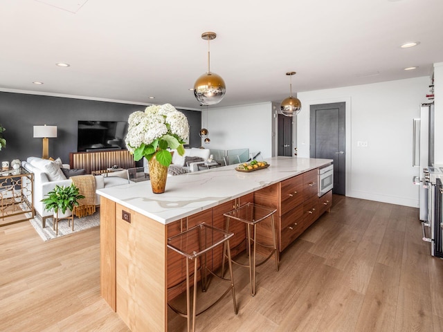 kitchen with light stone countertops, a spacious island, recessed lighting, light wood-style floors, and pendant lighting