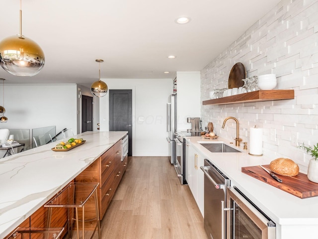 kitchen with a sink, light wood-style flooring, appliances with stainless steel finishes, brown cabinetry, and open shelves