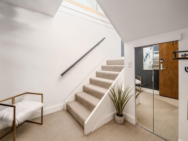 staircase featuring baseboards and carpet