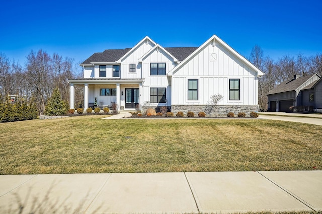 modern inspired farmhouse featuring covered porch, board and batten siding, and a front lawn