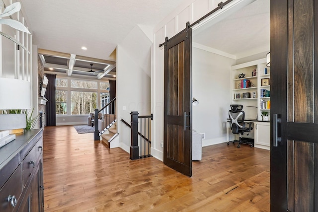 hallway with baseboards, beamed ceiling, a barn door, light wood-style flooring, and coffered ceiling