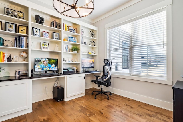 home office featuring a chandelier, built in desk, light wood-type flooring, and baseboards