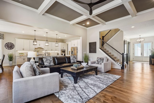 living room with beam ceiling, stairway, wood finished floors, and coffered ceiling